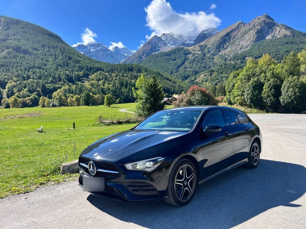 Berline noire, chaîne de montagne en fond.