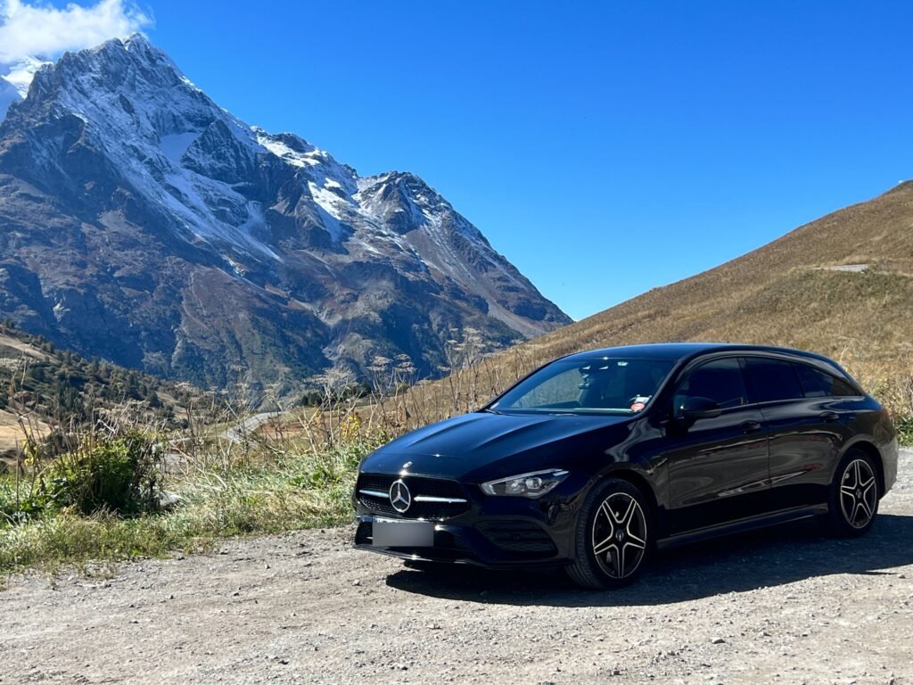 Mercedes noire, montagnes des Alpes enneigées derrière.